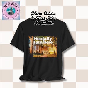 Puede incluir: Camiseta negra con un gráfico de una casa y el texto "Mentally I am here". El texto "More Colors & Kids Sizes Available" está en la parte superior de la imagen.