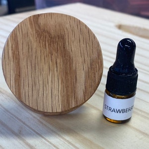 May include: A round wooden bottle stopper and a small amber glass bottle with a black dropper and a white label that says "STRAWBERRY".