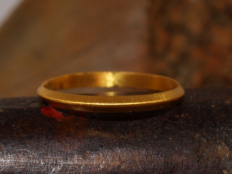 May include: A simple gold band ring with a smooth, slightly rounded surface.