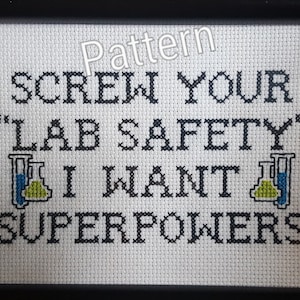 May include: A white cross-stitch pattern with black text that reads "Screw your "Lab Safety" I want superpowers" with two beakers on either side of the text.