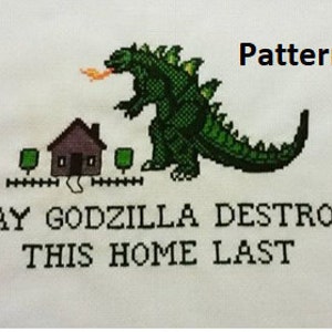 May include: Cross-stitch pattern featuring a green Godzilla destroying a small house with the text "May Godzilla Destroy This Home Last".