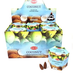May include: A box of HEM Coconut Backflow Incense Cones. The box is blue and white with a picture of coconuts on it. There are two incense cones in the foreground.