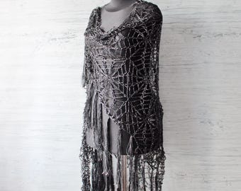 Può includere: Scialle in crochet nero con un motivo a ragnatela e frange. Lo scialle è drappeggiato su un manichino.