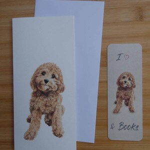 以下が含まれることがあります： 茶色のドゥードゥル犬のイラストが描かれた文房具セット。セットには、グリーティングカード、封筒、そして「I ♥ & Books」というテキストが入ったブックマークが含まれています。犬のイラストは、カードとブックマークの中央に配置されています。