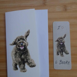 May include: A greeting card and bookmark set featuring a watercolor illustration of a playful, brown dog. The card is white, and the bookmark reads "I ♡ & Books."