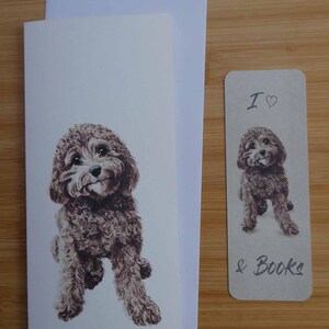 以下が含まれることがあります： 茶色と白の犬のイラストが描かれたグリーティングカードとブックマークのセット。カードには犬の全身画像が、ブックマークには犬の画像と「I ♡ & Books」の文字が描かれています。