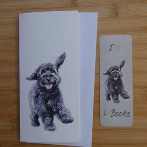 以下が含まれることがあります： 黒い犬のイラストが描かれた文房具セット。セットには、封筒付きの折り畳みカードとブックマークが含まれています。ブックマークには「I ♡ & Books」と書かれています。犬のイラストは白黒です。