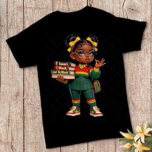 May include: Black t-shirt featuring a cartoon illustration of a young girl holding books. The girl wears glasses, a green skirt, and a red, yellow, and green sweater. The books read "Smart, Black, and Brilliant."