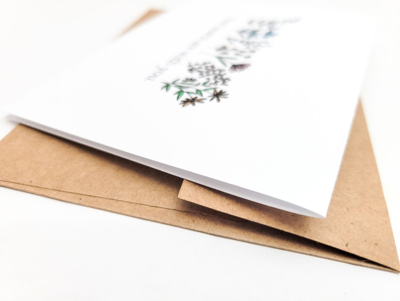 May include: A white card with a floral design and the text "Thank you for everything" printed on it. The card is folded in half and is sitting on top of a brown envelope.
