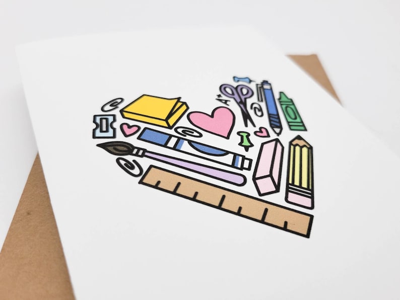 May include: A white card with a heart-shaped design made up of various school supplies, including a pencil, ruler, eraser, scissors, paintbrush, glue stick, paper clips, push pins, and a sticky note. The heart is outlined in black and filled with various colors, including pink, blue, yellow, green, and brown.