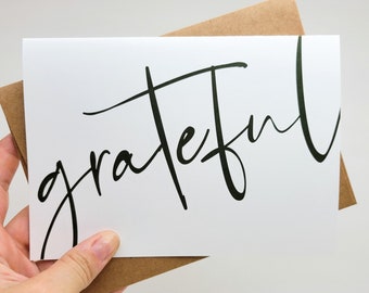 May include: A white card with the word "grateful" written in black calligraphy.