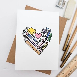 May include: A white card with a heart-shaped design made of various school supplies, including a pencil, ruler, scissors, eraser, and a sticky note. The heart is outlined in black and filled with various colors, including pink, blue, yellow, and green.