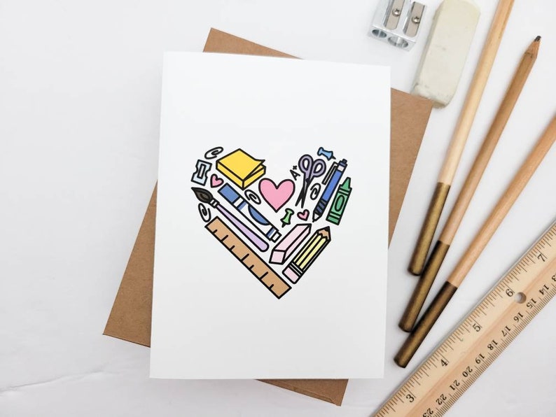 May include: A white card with a heart-shaped design made of various school supplies, including a pencil, ruler, scissors, eraser, and a sticky note. The heart is outlined in black and filled with various colors, including pink, blue, yellow, and green.
