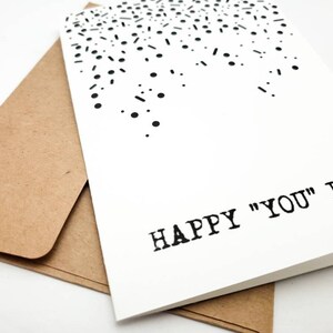 May include: A white card with a black confetti design and the text "HAPPY "YOU" DAY" printed in black.