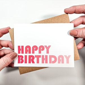 May include: A white card with a pink ombre gradient "Happy Birthday" greeting.