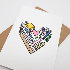 May include: A white card with a heart shape made of colorful school supplies, including a pencil, ruler, scissors, crayons, and a paintbrush. The heart is surrounded by a brown envelope.