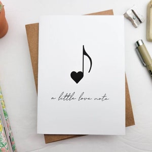 May include: A white card with a black musical note and a heart shape. The text "a little love note" is written below the note.