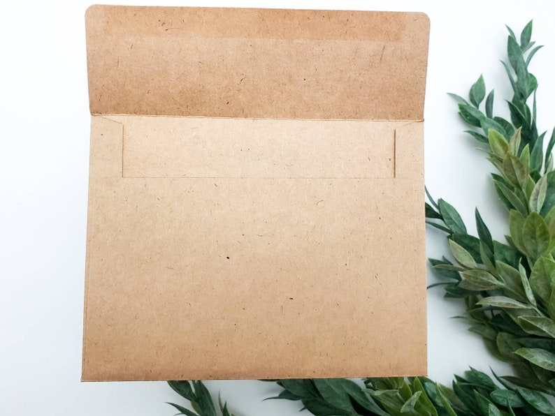 May include: A brown paper envelope with a white flap. The envelope is lying flat on a white surface.