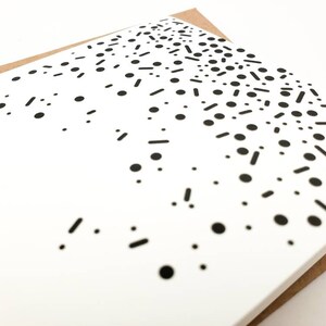 May include: A white card with a black and white confetti pattern. The confetti is made up of small circles and short lines.