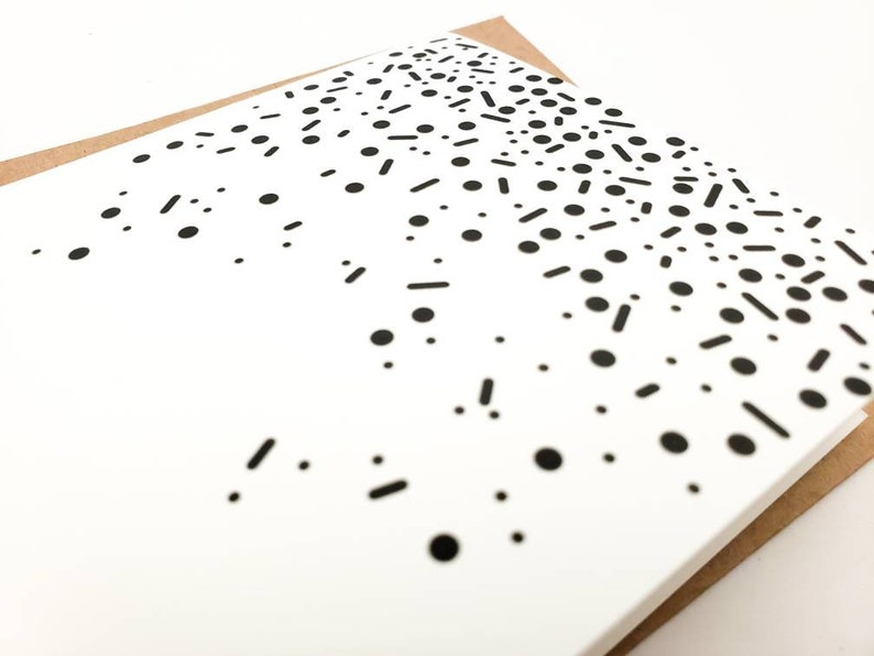 May include: A white card with a black and white confetti pattern. The confetti is made up of small circles and short lines.