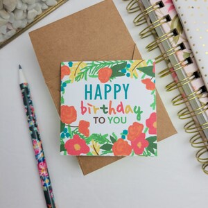 May include: A white card with a floral border and the text "HAPPY birthday TO YOU" in colorful letters.