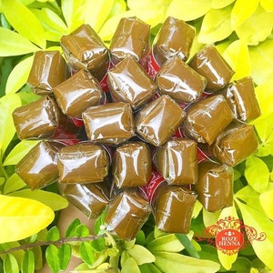 May include: A close-up of a bunch of brown henna cones wrapped in clear plastic. The cones are arranged in a circular pattern and are ready to be used for henna art.