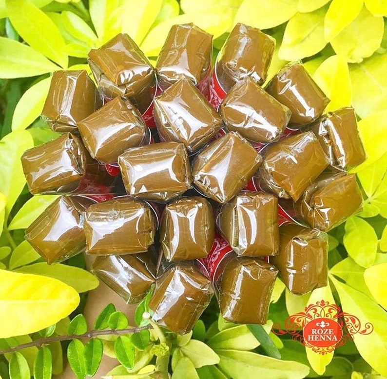 May include: A close-up of a bunch of brown henna cones wrapped in clear plastic. The cones are arranged in a circular pattern and are ready to be used for henna art.