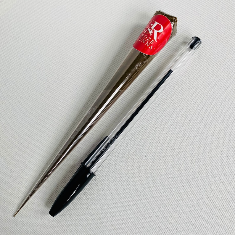 May include: A brown henna cone with the text "Roze Henna" and a black and clear pen.