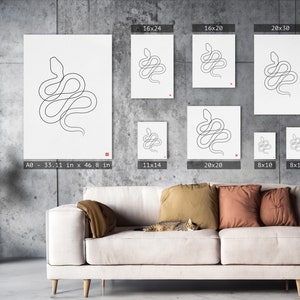 May include: White art prints with a minimalist line drawing of a snake. The prints are available in various sizes, including a large A0 size (84.1 cm x 118.9 cm). Each print has a small red square in the corner. The prints are displayed on a gray wall.