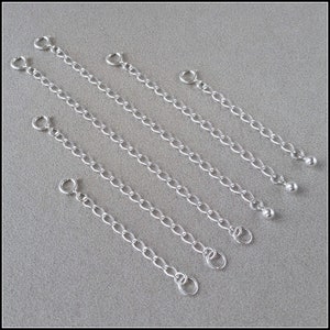 May include: Five silver chain extenders with jump rings and ball ends. The extenders are different lengths.