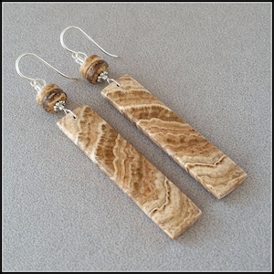 May include: A pair of dangle earrings with brown and white striped stone and silver beads.