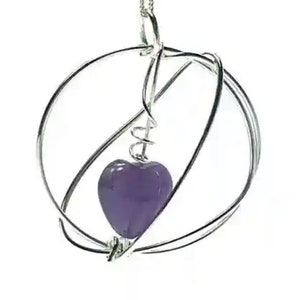 Amethyst heart gemstone set in a wire wrapped circular pendant on chain. Sterling silver jewellery UK design and made.