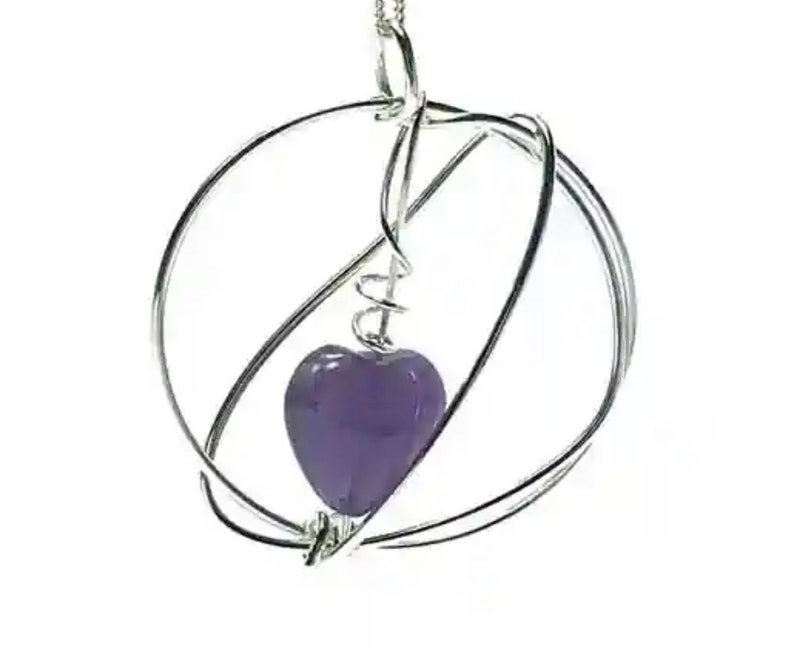 Amethyst heart gemstone set in a wire wrapped circular pendant on chain. Sterling silver jewellery UK design and made.