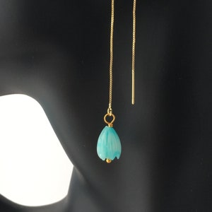 Könnte beinhalten: Ein Paar goldene Kettenohrringe mit einem türkisfarbenen, blumenförmigen Anhänger.