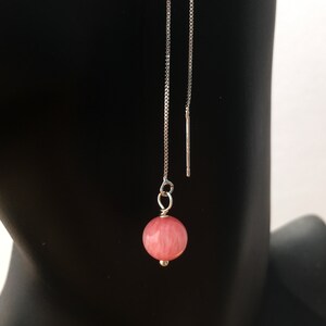 May include: A pair of silver chain earrings with a pink round gemstone pendant.