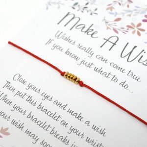 May include: Red string bracelet with gold beads and a card that reads "Make A Wish" with the text "Wishes really can come true If you know just what to do... Close your eyes and make a wish Then put this bracelet on your wrist When your bracelet breaks in two Then your wish may soon come true."