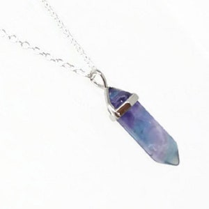 May include: A silver chain necklace with a purple and blue fluorite crystal pendant.