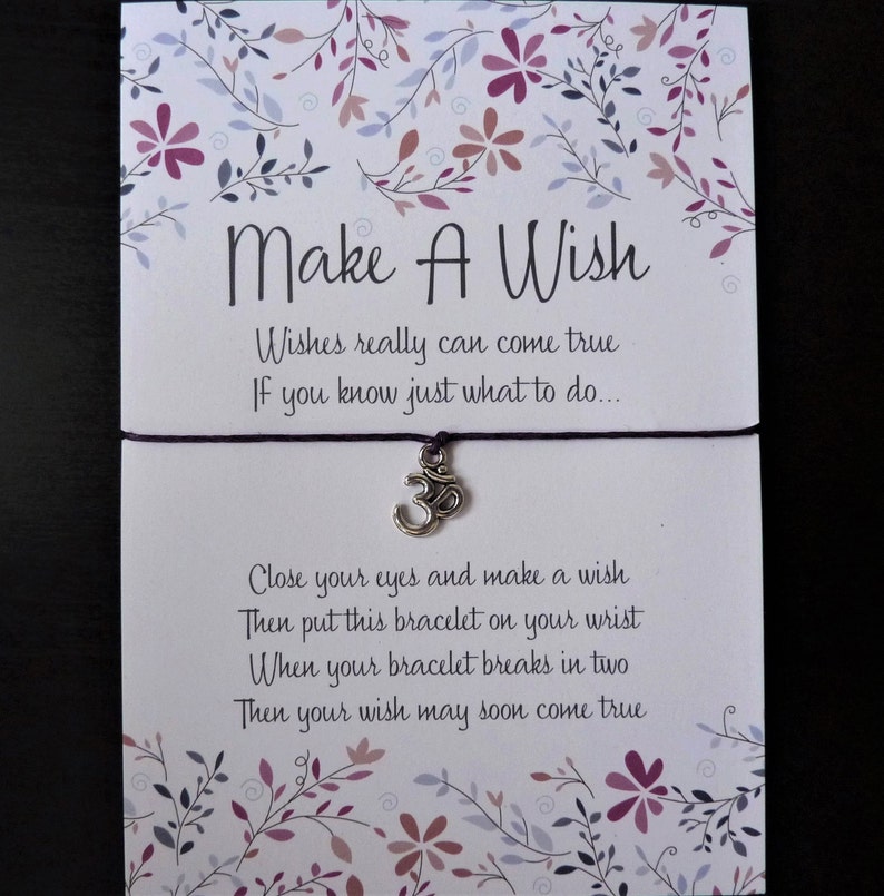 May include: A 'Make A Wish' card with a purple string bracelet featuring a silver charm. The card has floral designs in purple and pink. Text on the card reads: 'Wishes really can come true. If you know just what to do...'