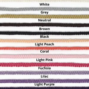 May include: A close-up of a selection of colorful cords in various shades. The colors include white, grey, neutral, brown, black, light peach, coral, light pink, fuchsia, lilac, light purple, and dark purple. Each cord is labeled with its color name.