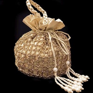 May include: A gold-colored, round drawstring bag with a woven net design. The bag features a braided handle and is adorned with multiple strands of white pearl beads, creating a luxurious and elegant accessory.
