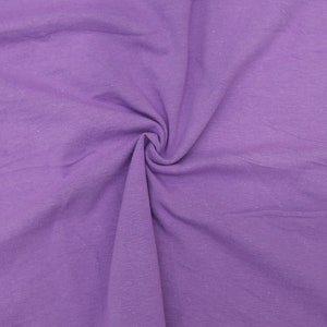 May include: A close-up shot of a swirl of lavender fabric. The fabric is a solid color with a slightly textured appearance. The material is gathered in the center, creating a spiral effect. The lighting is even, highlighting the fabric's texture.