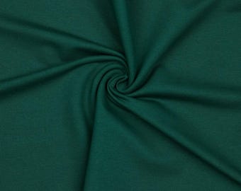 Könnte beinhalten: Nahaufnahme eines dunkelgrünen Stoffes mit feiner Textur. Der Stoff ist spiralförmig angeordnet, wodurch ein Gefühl von Tiefe und Bewegung entsteht. Die tief smaragdgrüne Farbe ist im gesamten Material gleichmäßig.