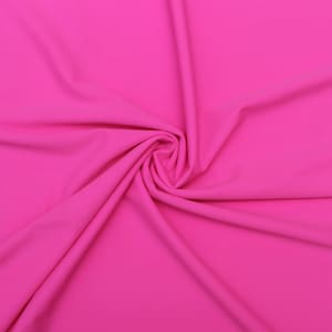 May include: A close-up of a bright pink fabric, showing its smooth texture and soft folds.