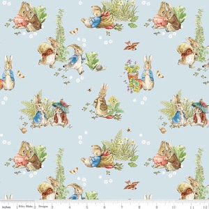 May include: Light blue fabric featuring a repeating pattern of watercolor illustrations. The design includes rabbits in various poses, butterflies, flowers, and other garden elements. The fabric has a whimsical, storybook aesthetic.