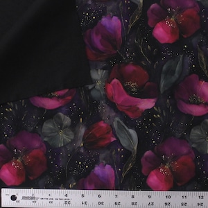 May include: A fabric featuring a dark black background with a vibrant floral pattern of magenta and deep purple poppies. The design includes scattered gold speckles and dark green foliage. A ruler shows a length of 12 inches at the bottom edge.