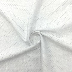 May include: Close-up of white fabric with a textured, dotted pattern. The material is folded and draped, creating shadows and highlighting the fabric's texture. The fabric appears to be lightweight and breathable.