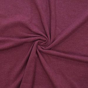May include: A close-up of a burgundy fabric with a soft, textured surface. The fabric is folded and draped, creating a smooth, flowing look.
