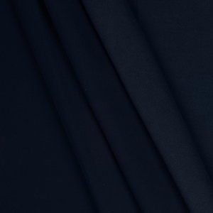 May include: A close-up shot of a navy blue fabric with soft folds. The fabric has a smooth texture and appears to be a medium-weight material. The folds create shadows and highlights, adding depth to the image. The overall impression is of a luxurious textile.