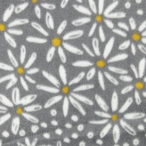 May include: Close-up of a gray fabric with a daisy pattern. White daisy petals surround yellow centers. The fabric has a soft, plush texture. The daisy pattern is repeated across the surface.