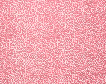 Könnte beinhalten: Ein Stoff mit einem sich wiederholenden rosa Leopardenmuster auf weißem Hintergrund. Ein weißes Maßband mit schwarzen Markierungen ist am unteren Rand sichtbar und zeigt Maße in Zentimetern von 0 bis 30 Zentimetern über die Breite.